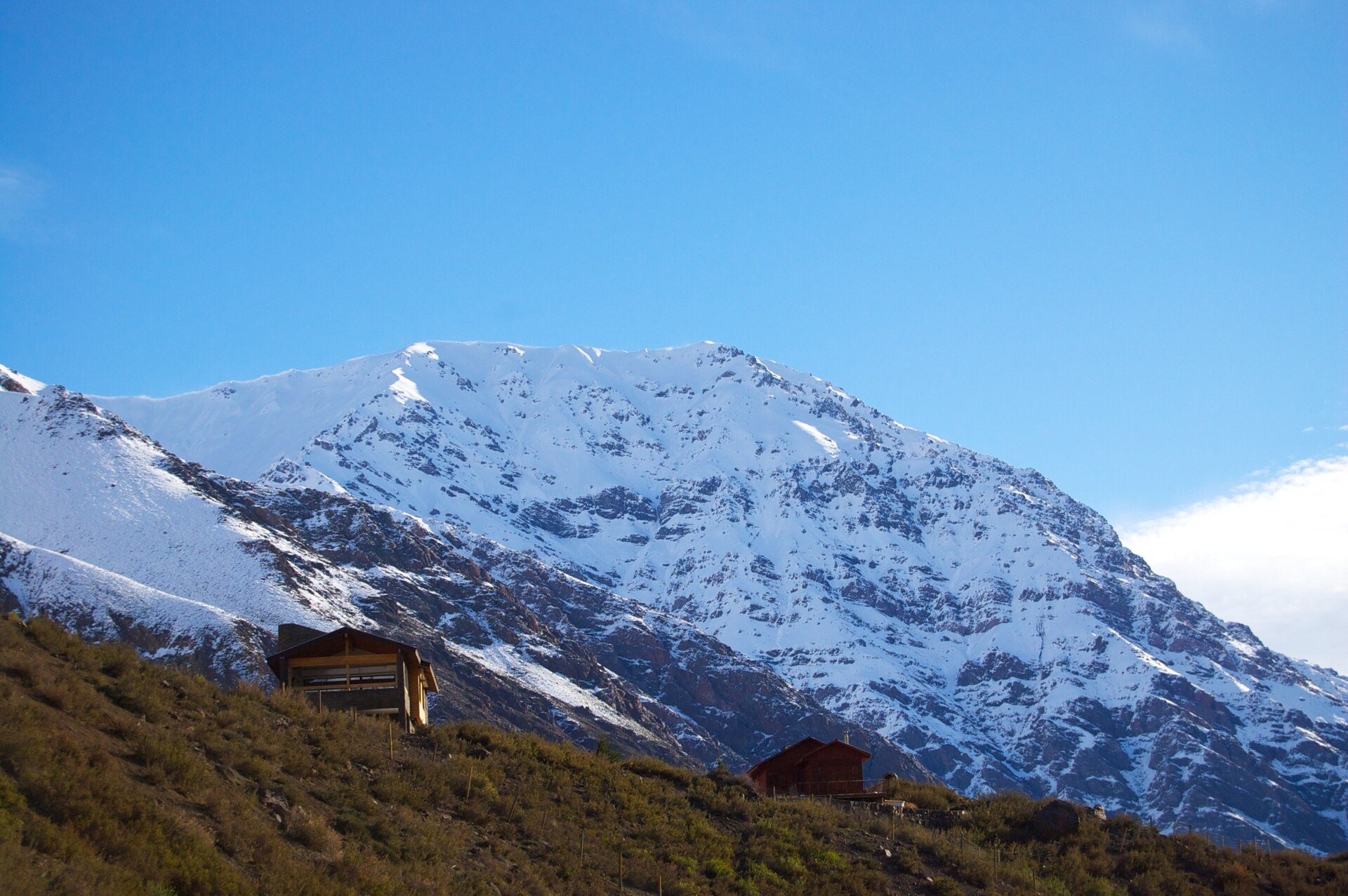 Small mountain buildings beneath broad snowy slopes in Cajón del Maipo