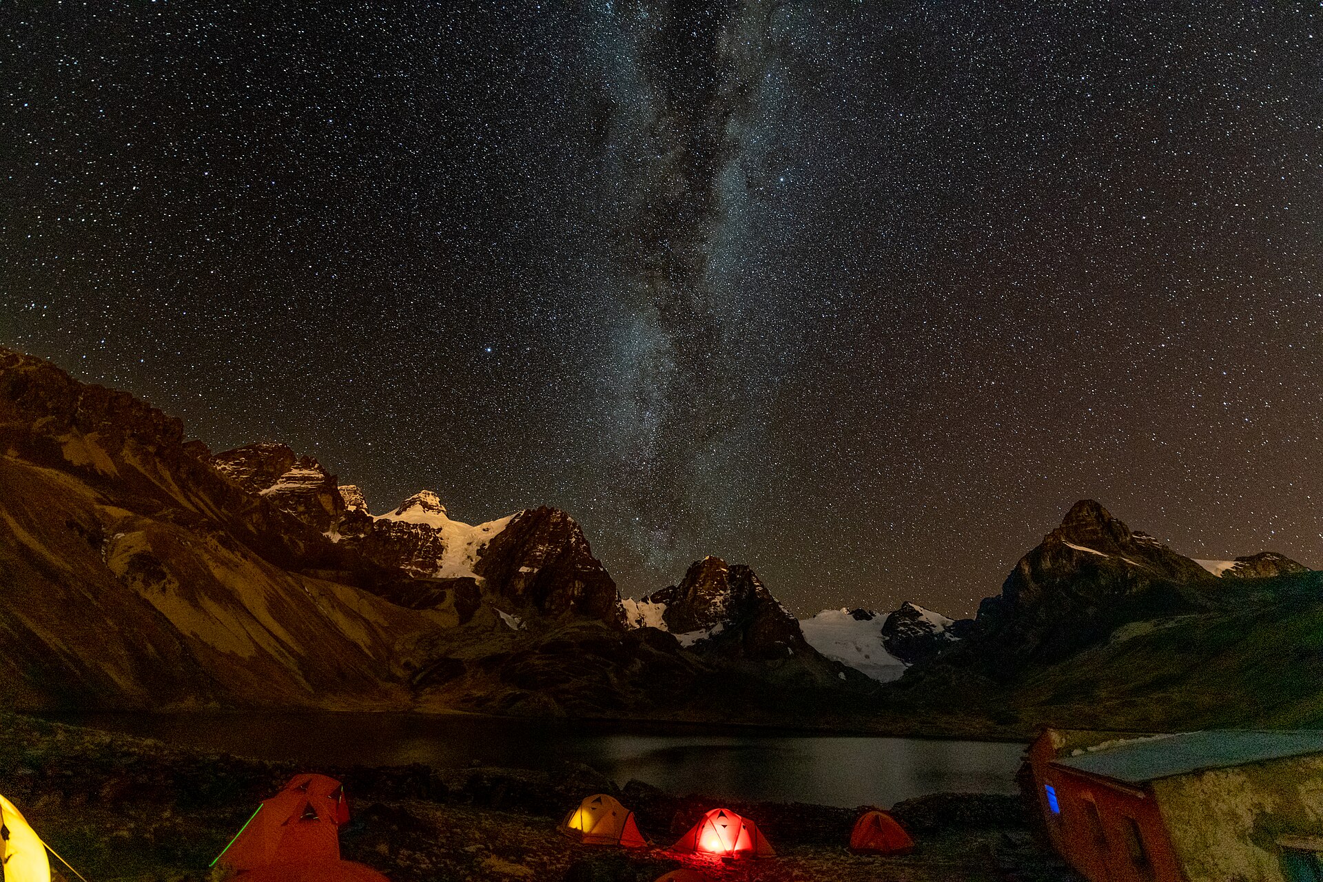 Tents beside Laguna Chiar Khota beneath the Milky Way and dark mountain silhouettes