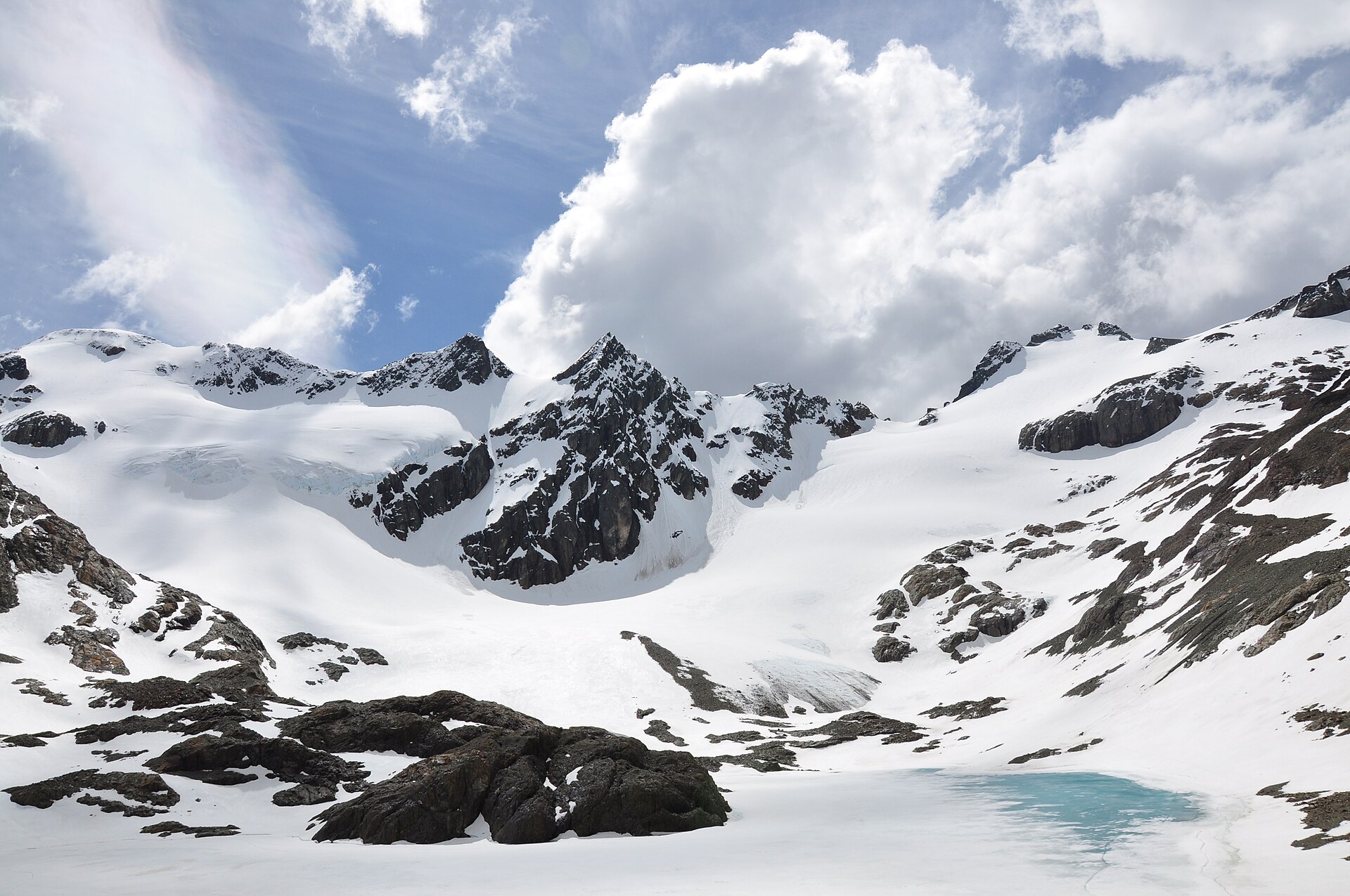 The snow-covered cirque and ice of Vinciguerra Glacier beneath broken peaks