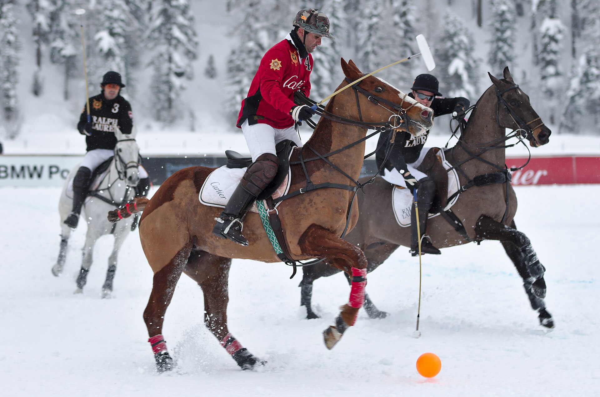 Polo players galloping across snow during a match at St Moritz